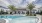 The pool area at our apartments in St Cloud, featuring reclining chairs, palm trees, and a view of the apartments. 